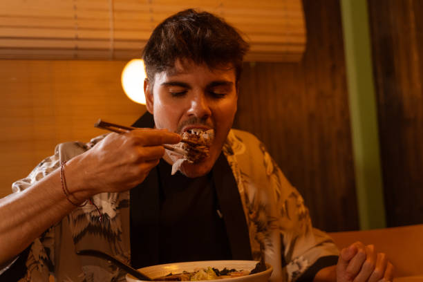 istock The young white-skinned brunette uses his chopsticks to devour an octopus dumpling while dining at a Japanese food restaurant. 1485574480