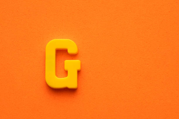 istock Yellow plastic letter G uppercase on orange foamy background 1485579378