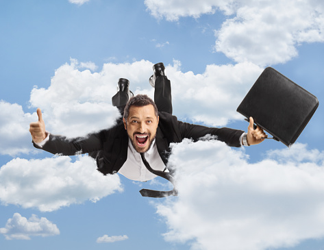 Businessman with a briefcase flying and gesturing thumbs up up in the sky