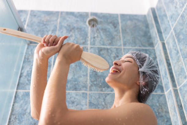 Small poodle with shower cap in the bathtub