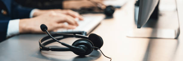 istock Panorama focus headset on call center workspace desk with blur operator. Prodigy 1485587374