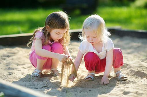 Little kid playing with sand and toys outdoors in summer. Child in park. Small girl at playground