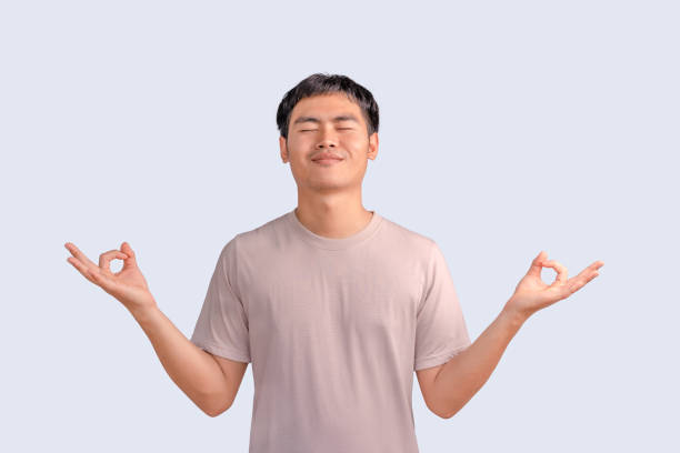 istock Happy smiling young man standing with closed eyes, having relaxation while meditating isolated on white background. Guy holds hands in yoga gesture, relaxing meditating, and trying to calm down. 1485596129