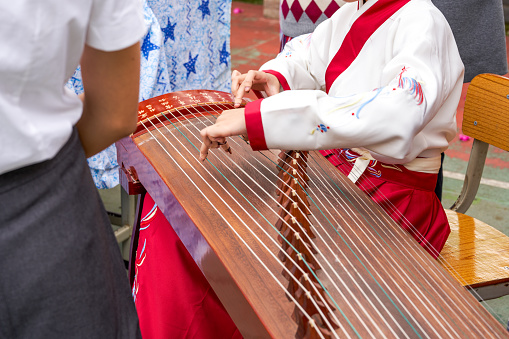 A little girl is playing the guzheng instrument