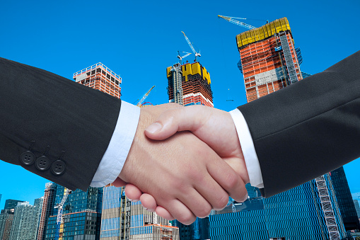 Businessmen handshaking in front of a construction site