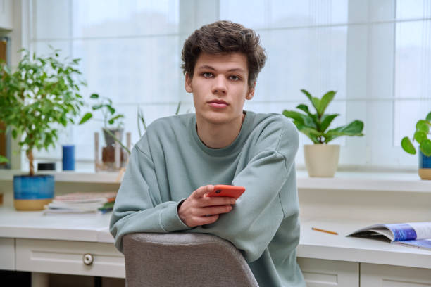 istock Handsome young guy with smartphone sitting in home interior 1485633282