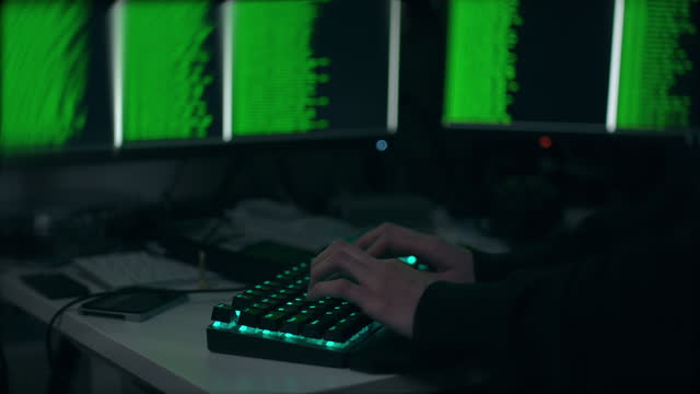 Unrecognizable Cyber Hacker Typing and Hacking a Computer System