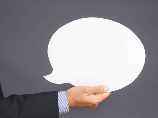 istock Businessman in suit hand holding an empty speech bubble paper while standing on a gray background. 1485647845