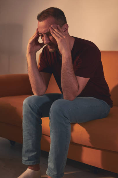 istock Man with headache sitting on a sofa at home. 1485648013