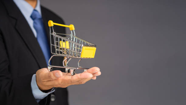 istock Businessman showing a mini shopping trolley on palm over a gray background. 1485648949