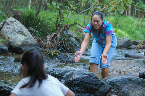 Family camping outdoor, Mother and daughters playing in the river. Mother and daughter go on an adventurous vacation trip together. Healthy lifestyle and eco-tourism.