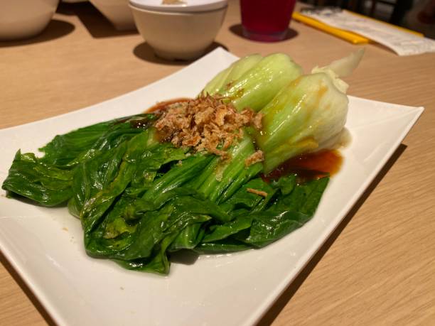 istock Dish of steamed bok choy with oyster sauce on white plate amid Asian style table setting 1485649549