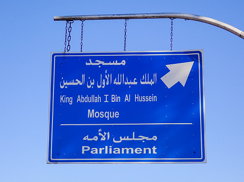 A road sign in Arabic and English in Abdali, Amman providing directions to a mosque and parliament.  This image was taken on sunny afternoon 64 April 2023.