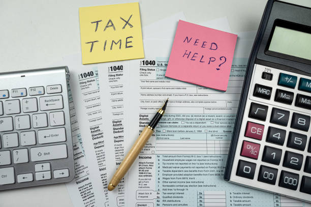 istock Text  TAX TIME with memo empty tax forms 1040 with pen calculator on desk 1485655247