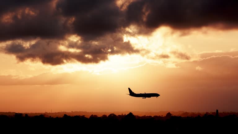 Jet airplane silhouette landing at the airport during sunset. Clouds and plane