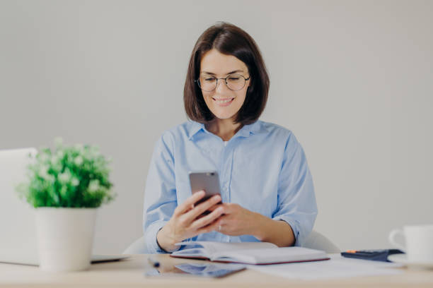 istock Happy female employee works on developing new project in office, searches information on websites via modern electronic gadgets, uses free internet connection in her cabinet, has happy expression 1485674437