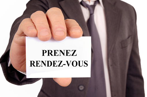 Businessman holding a card that says make an appointment in french