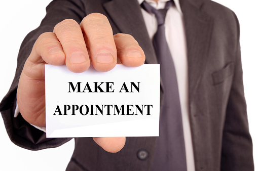 Businessman holding a card that says make an appointment