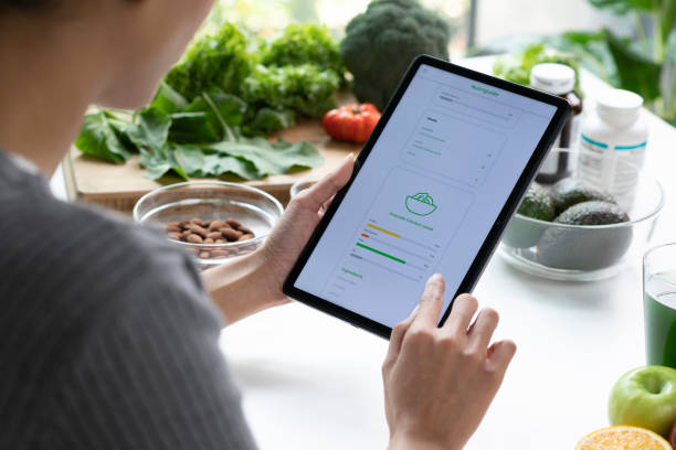 istock Woman Asian Professional Nutritionist busy working and checking data from a tablet with a variety of fruits, nuts, vegetables, and dietary supplements on the table 1485674928