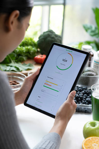 istock Woman Asian Professional Nutritionist busy working and checking data from a tablet with a variety of fruits, nuts, vegetables, and dietary supplements on the table 1485674951