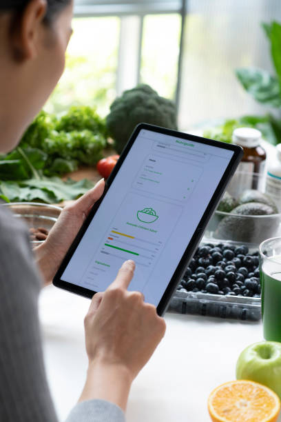 istock Woman Asian Professional Nutritionist busy working and checking data from a tablet with a variety of fruits, nuts, vegetables, and dietary supplements on the table 1485674958