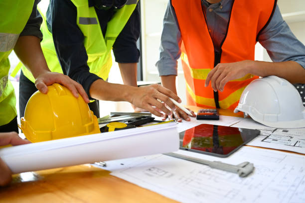 istock Team of architects wearing reflective jackets discussing construction process together in meeting room. 1485677067