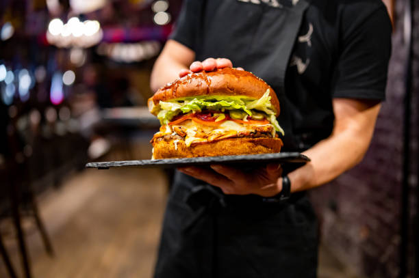 istock waiter hands hold a plate with a very big cheeseburger in pub 1485677120