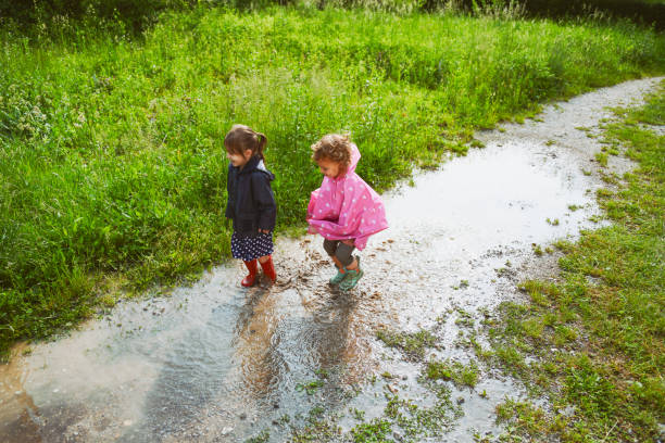 istock Two little girls jumping in mud puddles 1485680467