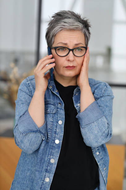 worried senior woman in glasses talking on the phone, close-up portrait. - news of the world imagens e fotografias de stock