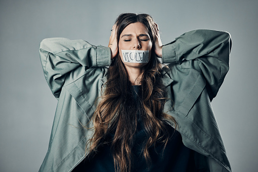 Woman, protest and tape on mouth in fear for cold war, armageddon or doomsday against gray studio background. Female activist with hands on head and message to stop or end global violence in society