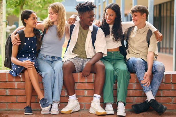 istock Portrait Of Multi-Cultural Secondary Or High School Students Sitting On Wall Outdoors At School 1485686189