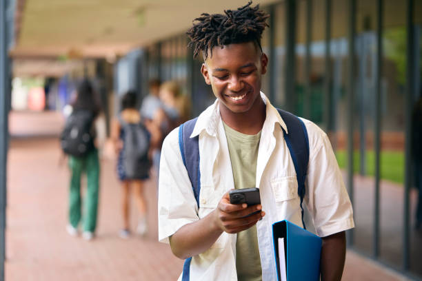 istock Male Secondary Or High School Student Outdoors At School Going To Class Looking At Mobile Phone 1485686359