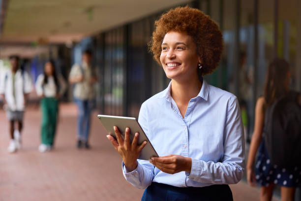 istock Smiling Female High School Or Secondary School Teacher With Digital Tablet Outdoors At School 1485686410