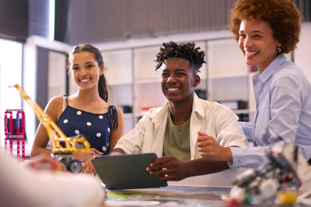 istock Female High School Teacher With Digital Tablet Helping Students In STEM Technology Lesson 1485688438