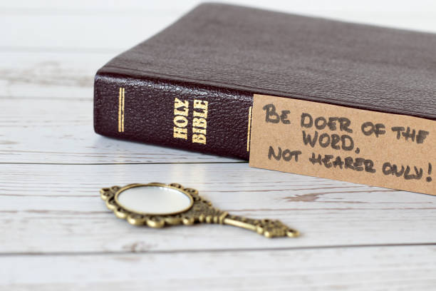 sii facitore della parola, non solo uditore, versetto scritto a mano con libro sacro biblico chiuso e antico specchio dorato su legno - righteous foto e immagini stock