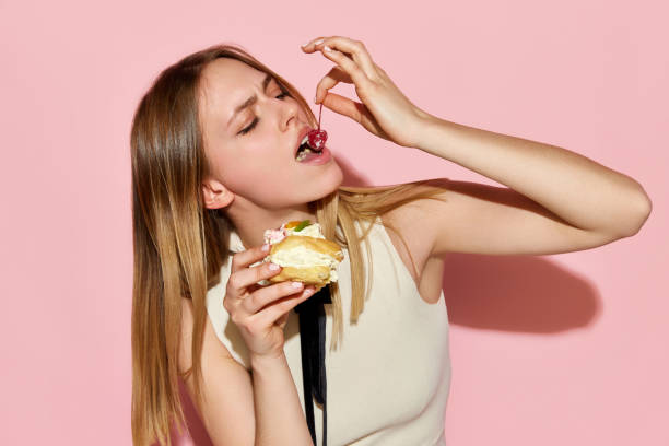 istock One beautiful model eating cake with pleasure facial expression over pink background 1485691507