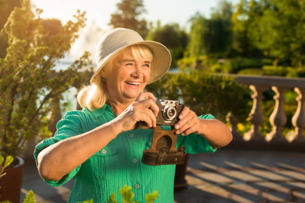 Smiling woman with camera. Senior lady in summer hat. Inspiration is easy to find. Photographer in good mood.