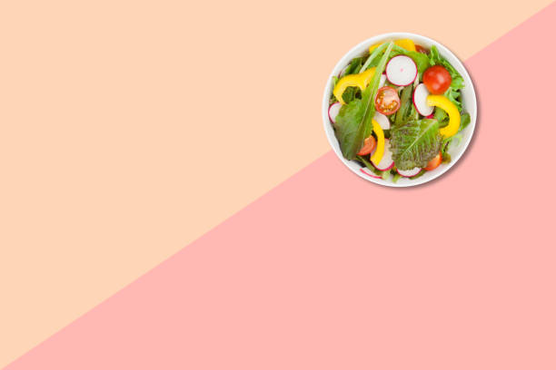 istock Close up view vegetable salad on brown plate isolated on pink background. 1485694119