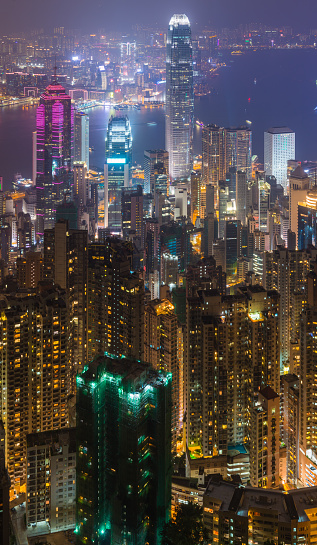 Aerial view over Victoria Harbour at night, from the glittering skyscrapers of Wan Chai and Central across the busy waterway to the crowded high-rises of Kowloon and Mong Kok in the heart of Hong Kong, China.