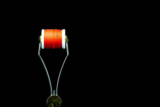 Fishing fly tying bobbin holder tool with thread on a black background