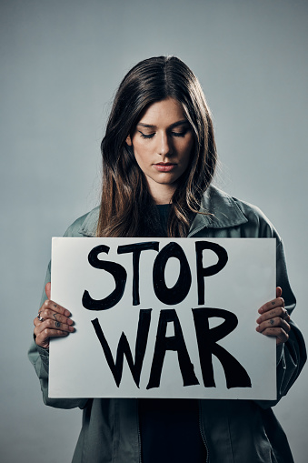 War, stop and sad woman with a sign as a voice isolated on a grey studio background. Protest, crime and girl with a board against conflict, violence and danger with an opinion in Russia on a backdrop