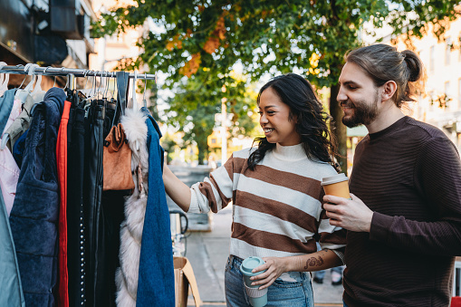 A millennial couple is taking a look at a second-hand clothing store. They are hanging out together in Bushwick, Brooklyn.