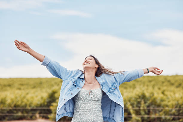 Happy, freedom and smile with woman in nature for peace, relax and youth with blue sky mockup. Journey, adventure and happiness with girl enjoying outdoors for summer break, vacation and holiday stock photo