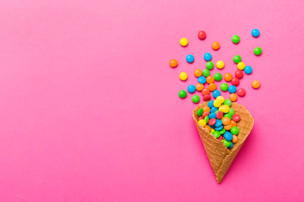 istock waffle cone full of assorted traditional candies falling out on colored background with copy space. Happy Holidays sale concept 1485709513