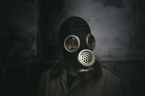 A man wearing a gas mask staying in the dark in a dilapidated building, book cover