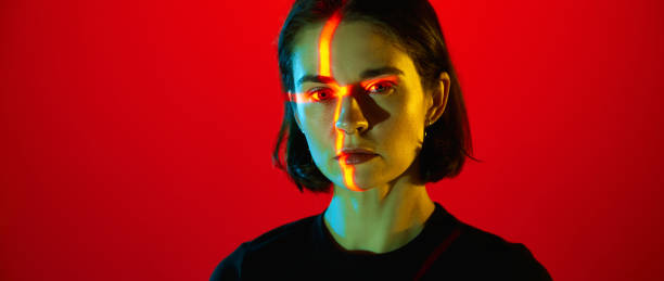 istock One charming woman with piercing in nose looking at camera with emotionless face over red neon background. Banner with copy space. Banner with copy space. 1485716644