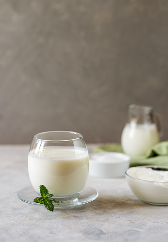 Ayran is a popular refreshing Asian beverage made with yogurt, water and salt. Fermented drink Ayran is a source of nutrients, minerals and probiotics. In the picture Ayran in glass with main ingredients and mint. Copy space. Vertical banner