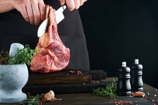 istock Chef cutting steak beef. Mans hands hold raw steak Tomahawk on rustic wooden cutting board on black background. Cooking, recipes and eating concept. Selective focus. 1485717721