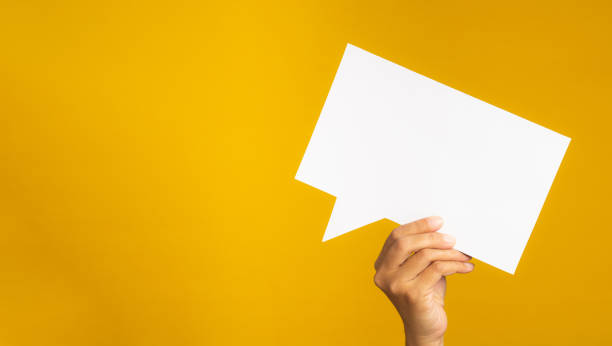 istock Concept of a speech bubble. Hand holding an empty speech bubble on a yellow background. 1485721798