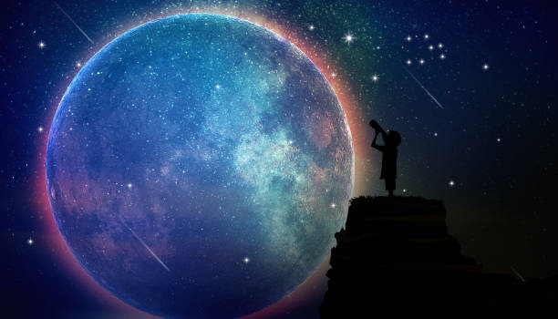 istock Boy standing on a rock using a telescope looking at the stars in full moon night 1485721906